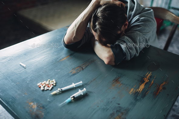 Male junkie at the table with drugs and syringe - Stock Photo - Images