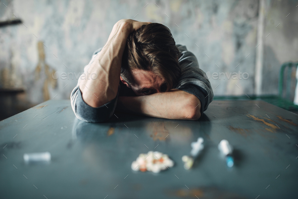 Male junkie at the table with drugs and syringe - Stock Photo - Images