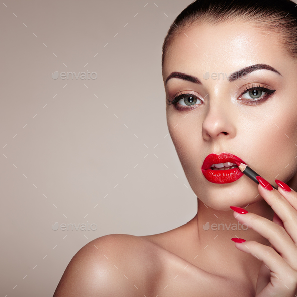 Beautiful woman paints lips with lipstick - Stock Photo - Images