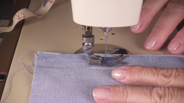 Women's Hands Stitch the Fabric on the Sewing Machine