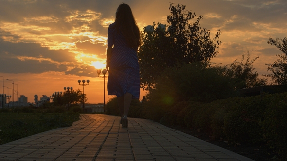 Girl Walking Away Through Park at the Sunset alt