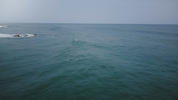 Drone Camera Turning Left Following Big Ocean Wave Reaching the Coast, Foaming and Crashing on a alt