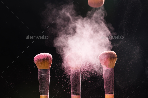 Mineral makeup and beauty concept - Makeup brushes in pink powder over dark background Stock Photo by Satura_