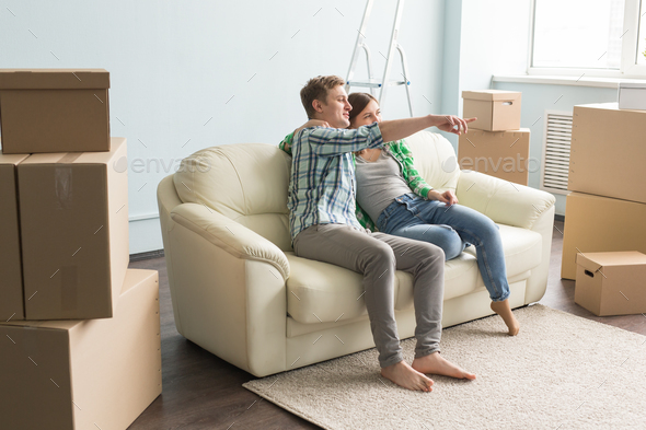 Just moved young couple on sofa planning interior in a new house. Stock Photo by Satura_