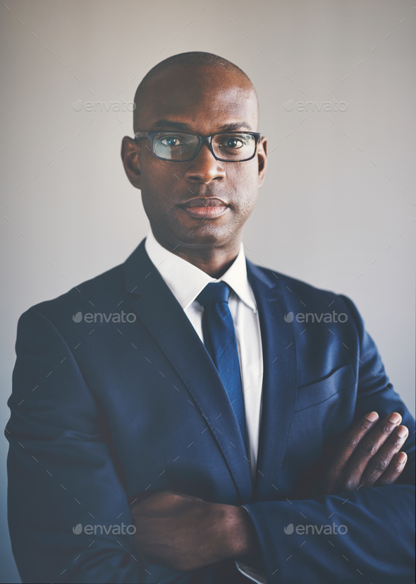 African executive in a suit standing wth his arms crossed - Stock Photo - Images