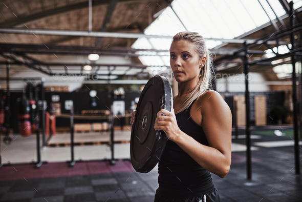 Fit young woman carrying weights for a gym workout Stock Photo by UberImages