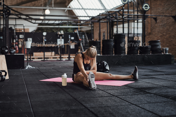 Young woman stretching on a gym floor before working out Stock Photo by UberImages