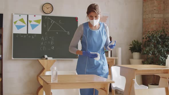 Cleaning Lady Disinfecting and Wiping School Desks in Classroom alt