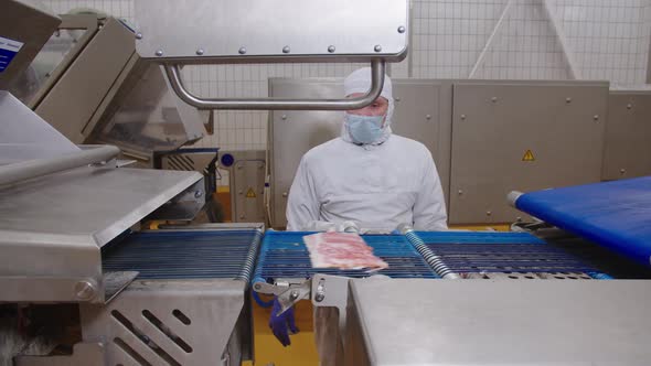 Worker Sets Up Automated Bacon Cutter Removal Process in Production Facility