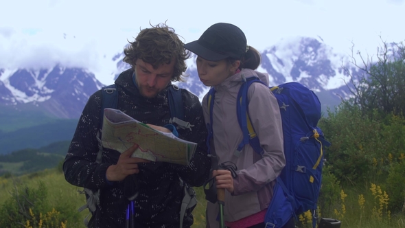 Multiethnic Сouple Standing on a Mountain Path Looking at a Map While Standing on a Mountain Path