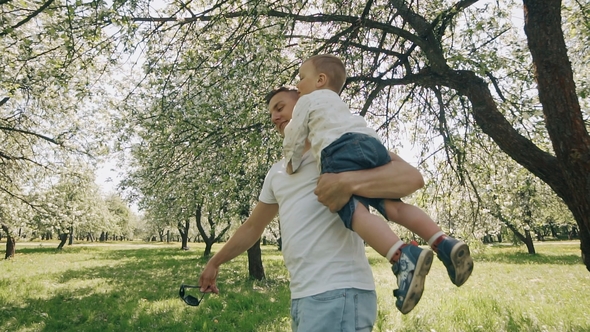 Father and Son Playing at Park. Father Raises Child in Arms. Fatherhood Concept