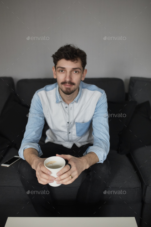 Freelancer resting with a cup of coffee on a couch while thinkin - Stock Photo - Images