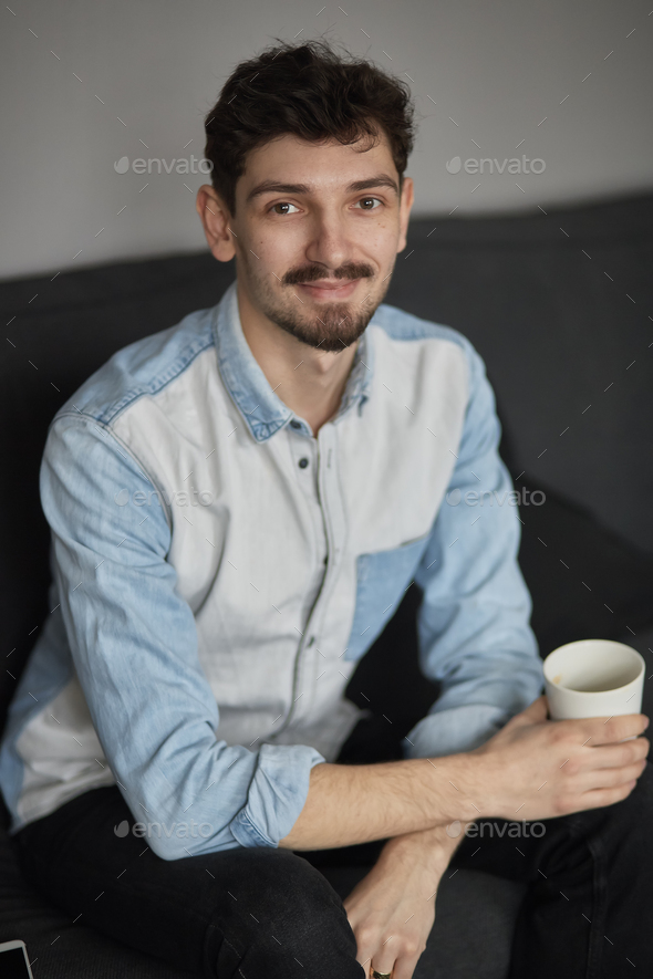 Freelancer resting with a cup of coffee on a couch while thinkin - Stock Photo - Images