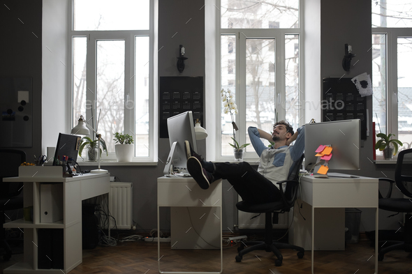 A man thinking of a vacation in a modern office while relaxing - Stock Photo - Images