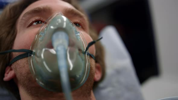 Injured Man in Oxygen Mask Lying on Stretchers in Ambulance Car alt