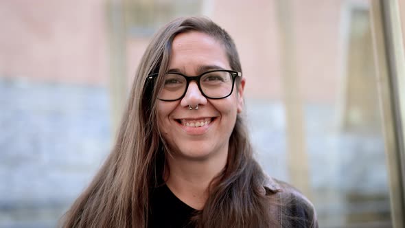 Portrait of a Young Hipster Woman in Eyeglasses Looking at the Camera and Smiling alt