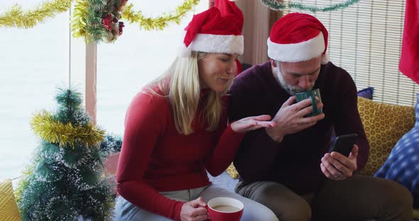 Happy caucasian mature couple making video call in room full of christmas decorations alt