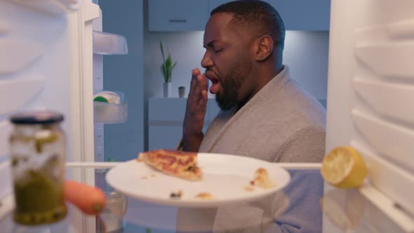 Sleepy man opening the empty refrigerator and looking inside searching for something to eat.