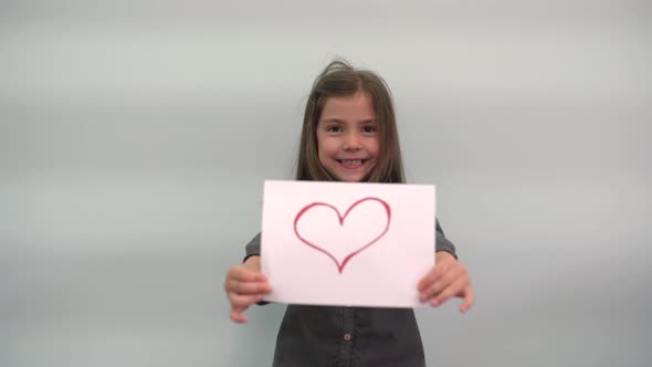 A Girl Holds a Piece of Paper with a Heart Drawn on It and Smiles A Child Turns a Sign with a Heart