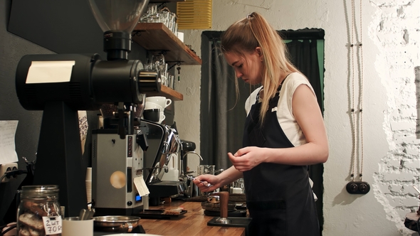 Pretty Young Female Barista Weighing Coffee Grains on a Scale Before Brewing a Cup of Coffee alt