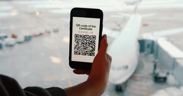Passenger Shows Fake and Nonactive QR Code in Airport on Screen of Smartphone alt