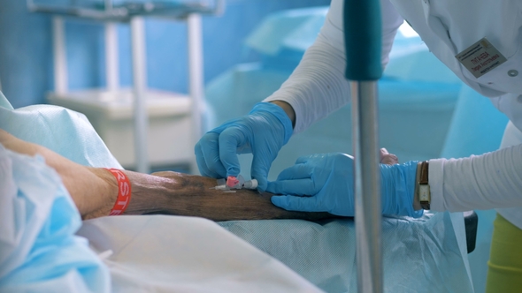 Doctor Inserts a Needle Into Patient's Vein alt