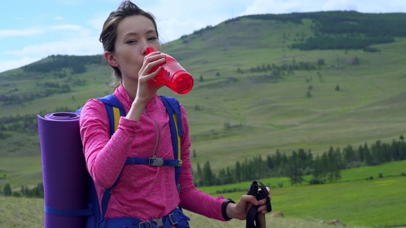 Woman Taking a Break To Drink From Water Bottle While Hiking.