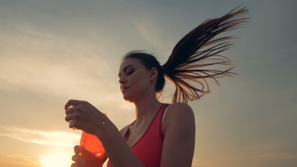 Slim Good-looking Woman Is Running in the Fresh Air and Drinking From a Bottle alt