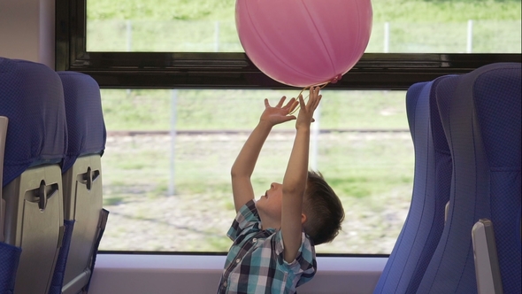 Cute Little Boy Playing with Pink Balloon in the Train, While It Moving. Child Going on Vacations