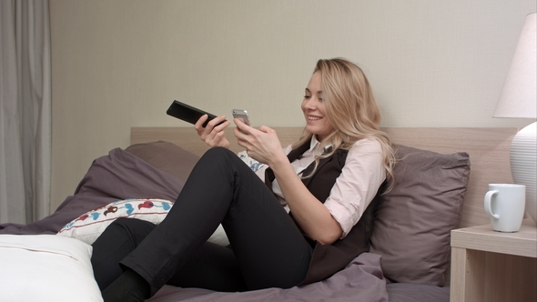 Girl Watching TV, While Using Smartphone in Bed alt