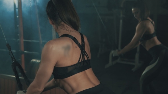 Woman Training with Weight-lifting Training Machine in  in Dark Gym