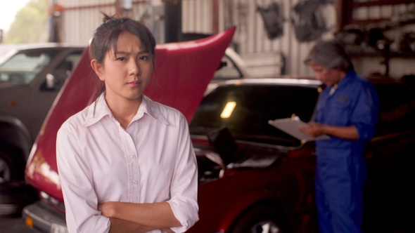 Portrait of Angry Customer While a Mechanic Works on a Car in the Background