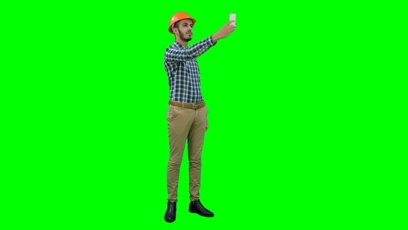 Smiling Construction Worker Using Phone To Take Selfies on a Green Screen alt
