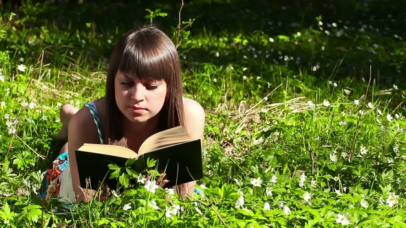 Beautiful Girl Reading a Book in Forest on Flowers Field
