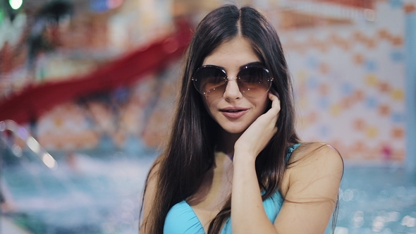 Sexy Young Women in Blue Swimsuit and Sunglasses Posing in Pool. Portrait of an Attractive Girl alt