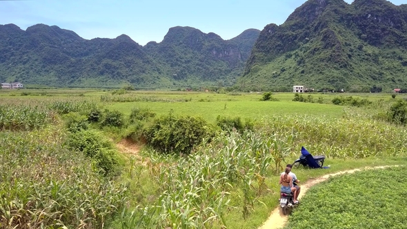 Couple on Motorbike Passes By Local Man on Road Side alt