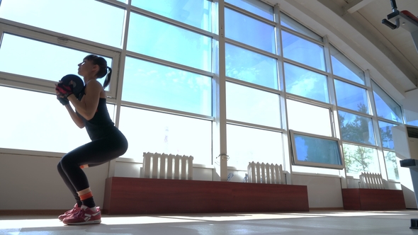 Sportive Young Woman with Dumbbell in Hands Doing Sit-ups in the Fitness Room