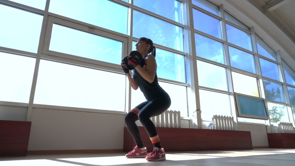 Sportive Young Woman with Dumbbell in Hands Doing Sit-ups in the Fitness Room