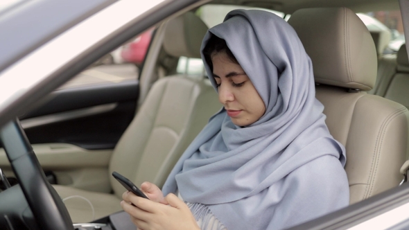 Beautiful Young Woman in Hijab Web Surfing in Her Car, Zoom Out Shot