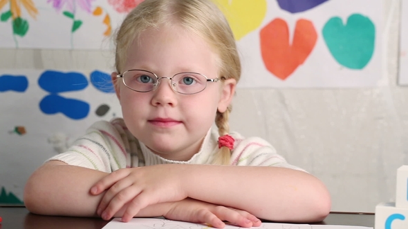 Beautiful Little Girl in Glasses with a Pencil Draws
