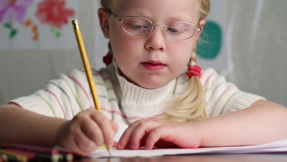 Beautiful Little Girl in Glasses with a Pencil Draws