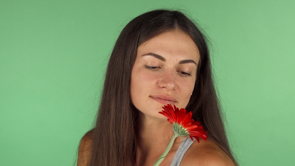 Gorgeous Woman Smiling Looking Away Dreamily Holding a Flower alt