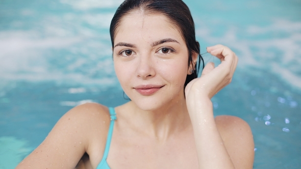 Young Sexy Woman in Blue Swimsuit Posing in Pool with Turquoise Water