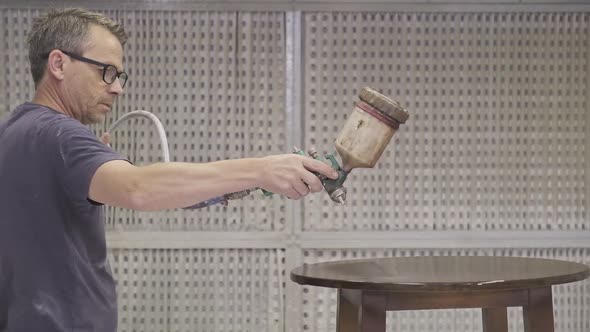 Workman using airbrush for applying flame retardant to wood detail ensuring fire protection alt