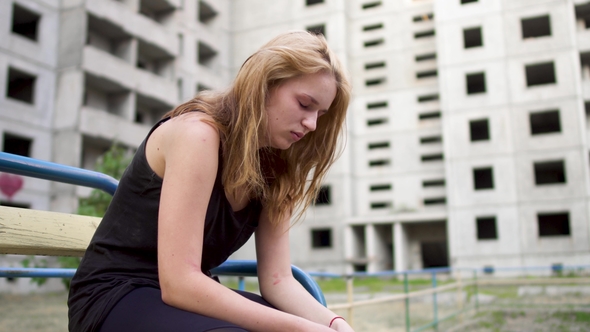 Nervous Girl Is Sitting Near High Building alt