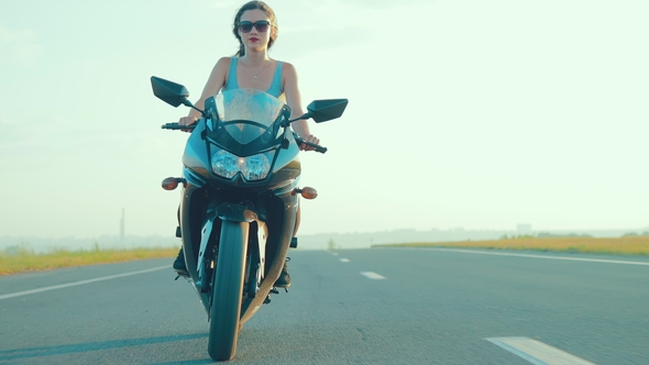 Young Girl with Brown Hair Rides a Motorcycle During Sunset alt
