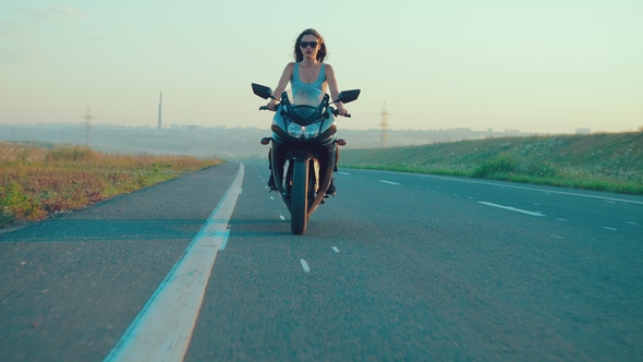 Girl at the Wheel of a Motorcycle Parked on the Roadside Outside the City During Sunset alt