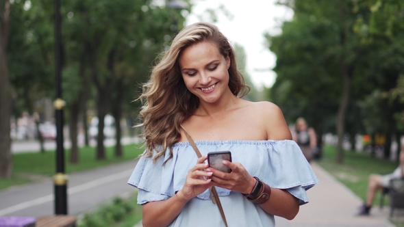 Female Typing Message on Smartphone and Is on Boulevard alt