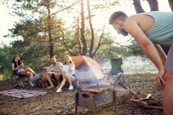 Party, camping of men and women group at forest. They relaxing, singing a song and cooking barbecue Stock Photo by master1305