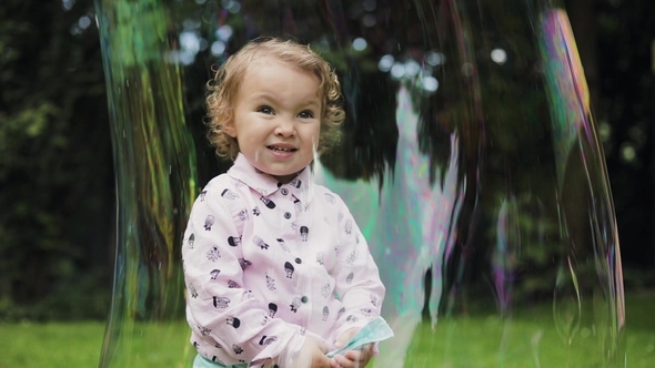 Little Curly Girl in Huge Bubble Feeling Happy. . Bubble Show.